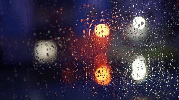 雨滴滴在玻璃上外面是个漆黑的夜晚电灯的散景抽象的图片透明的玻璃湿表面外面天气不好