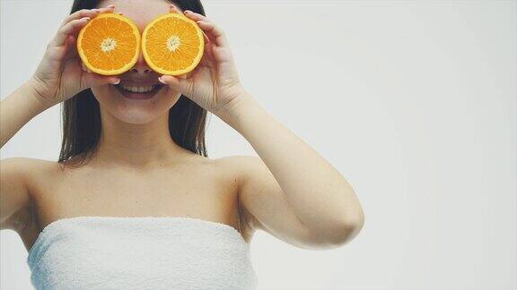美丽的肖像一个美丽的年轻女子摆姿势与橙色的水果孤立在白色的背景关闭他的眼睛