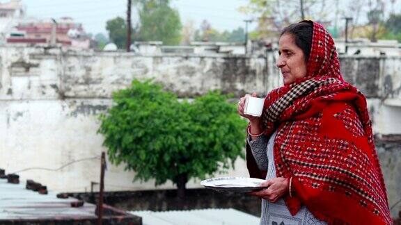 印度农村成熟的妇女在清晨喝茶
