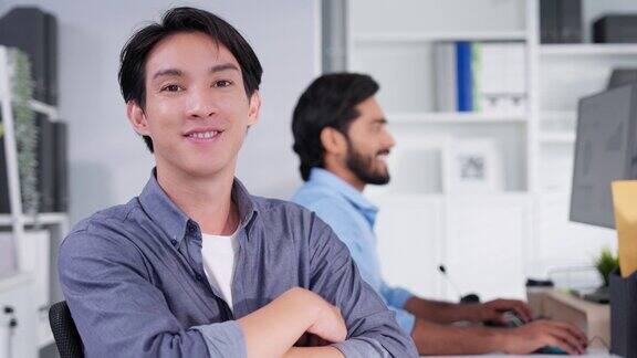 迷人的年轻亚洲商人的肖像微笑在办公室的办公桌工作空间自信的人情绪高兴业务工作者