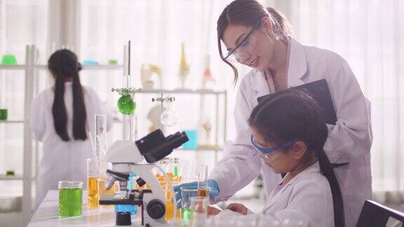 快乐的小学女孩和老师在进行科学实验时预期化学反应