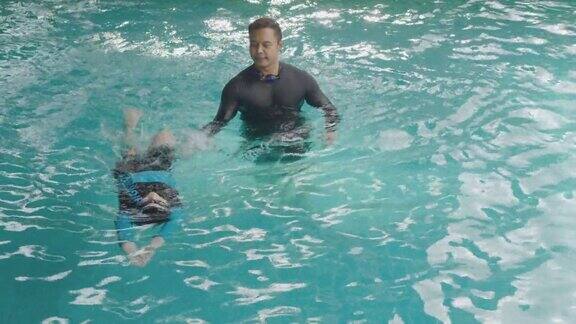 亚洲男孩在游泳池学游泳