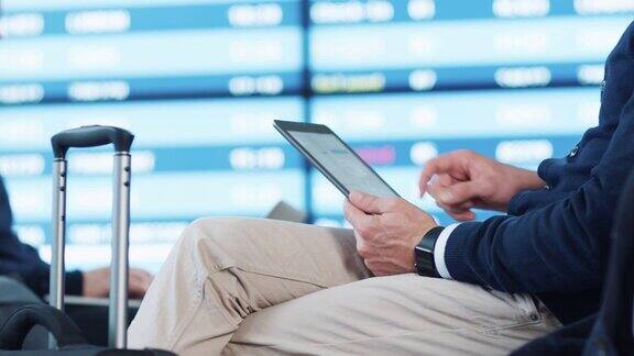 一名男子在机场候机室等候登机时使用平板电脑