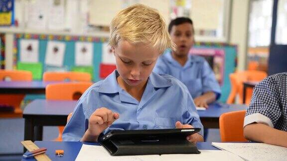 小男孩在学校教室里使用平板电脑
