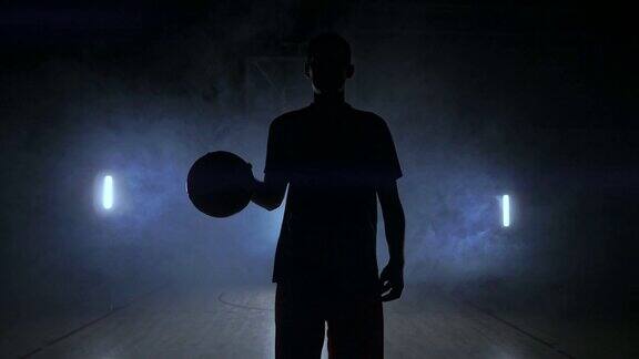 男篮球运动员在烟雾中移动在摄像机敲打球周围的木地板在慢动作斯坦尼康镜头