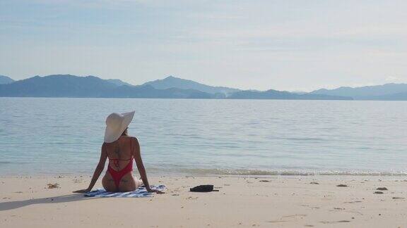 穿着泳装和太阳帽的女人在海滩上晒太阳