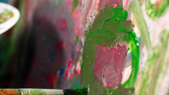 现代艺术一个女人用调色板上的颜料用画架在画布上画画