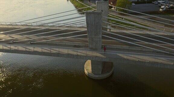 日落时分在桥上的空中城市慢跑者
