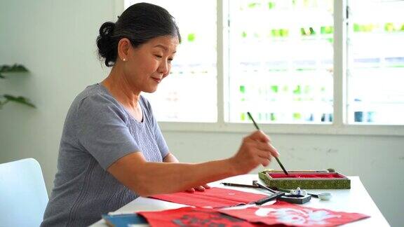 年长的亚洲妇女在家里练习中国传统书法