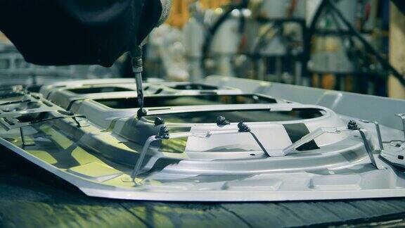 一个工厂工人正在往车门的框架上涂胶水汽车制造厂汽车生产汽车生产线
