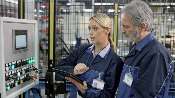 工厂女员工向男同事展示输入到机器屏幕触摸屏上的数据