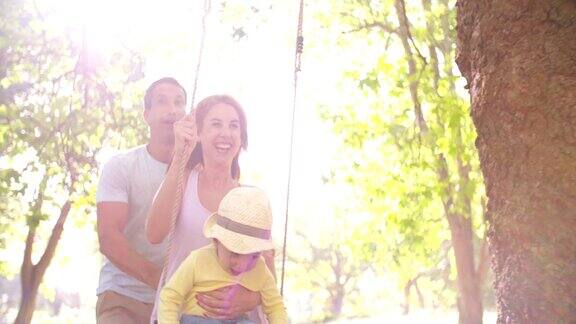 一家人和一个小女孩在公园里快乐地荡秋千