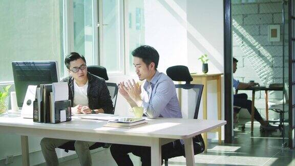 两个年轻的亚洲企业家在办公室里讨论生意