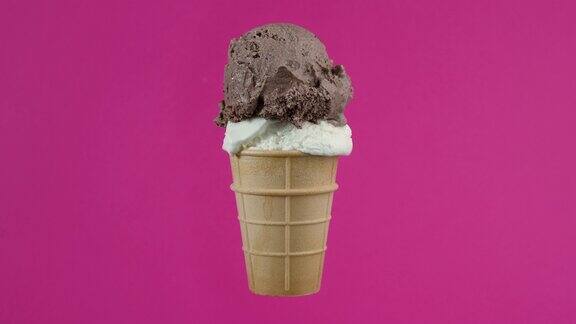 巧克力和香草冰淇淋球在华夫筒粉红色的背景旋转的软奶油冰淇淋冰淇淋球在华夫筒彩色背景