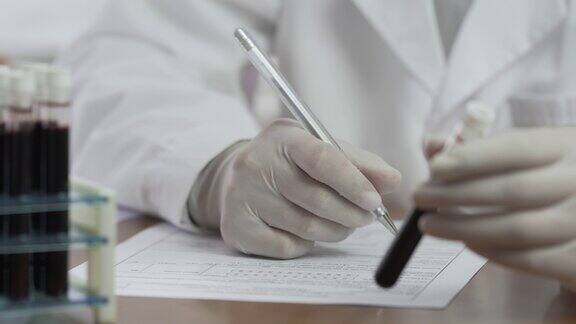 医生或化验室技术员一手拿着化验室血液试管一手在病人病历上写下结果