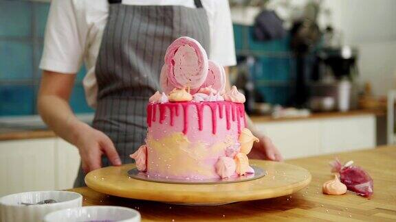 难以辨认的糕点厨师旋转摊位新鲜制作的粉色滴漏蛋糕装饰奶油糖霜手工蛋白霜和糖珍珠