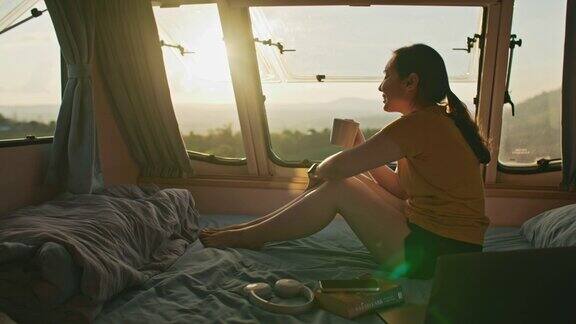 度假期间女性在货车里放松年轻女子乘坐露营车欣赏山景