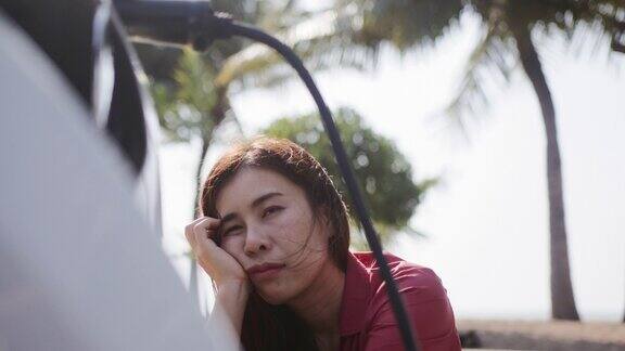 无聊的亚洲女人等着电动汽车充电