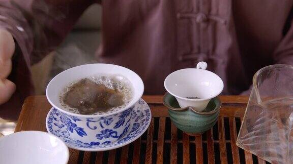 男子将热水倒在茶盖丸上放在木托盘上冲泡师傅用玻璃壶泡茶传承东方茶道传统