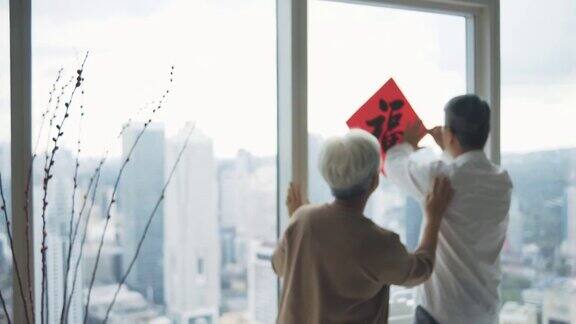 中国新年老夫妇装饰房子的客厅窗户上的中国书法装饰准备家庭团聚