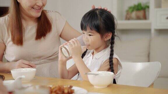 母亲在早餐时给女儿端上牛奶家庭关系概念健康食品