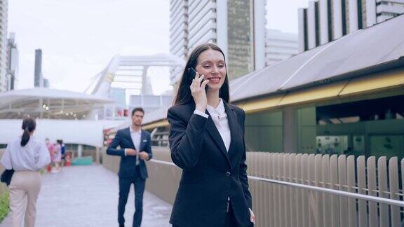 白人年轻女商人在城市里散步时用智能手机说话迷人美丽的女员工在户外与同事端着咖啡用手机自信地交流