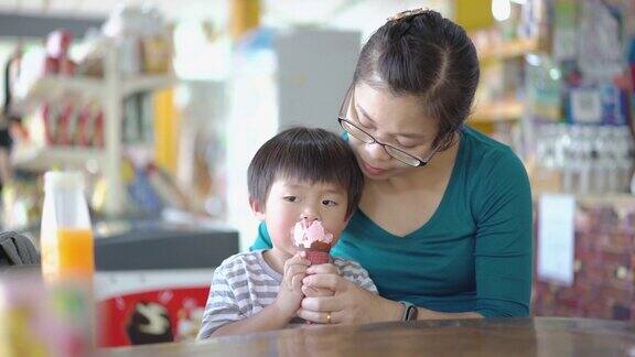 亚洲小男孩和妈妈在小店里吃冰淇淋
