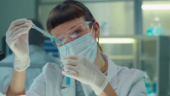 实验室女科学家将蓝色化学物质注入试管