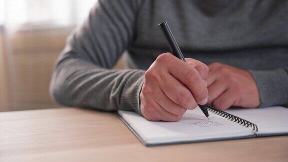 一个无法辨认的男人用钢笔在笔记本纸上写备忘录