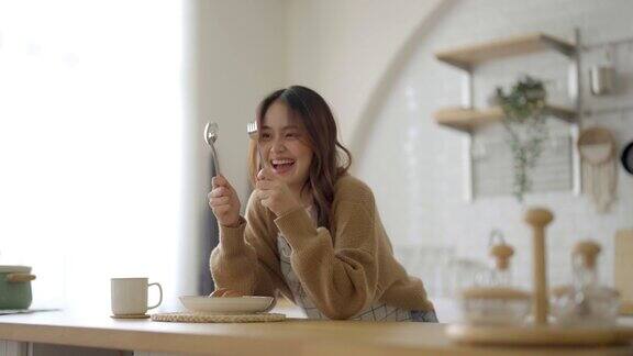 快乐的年轻亚洲女人穿着围裙站在厨房的房间美丽的女性微笑着看着镜头感觉自信