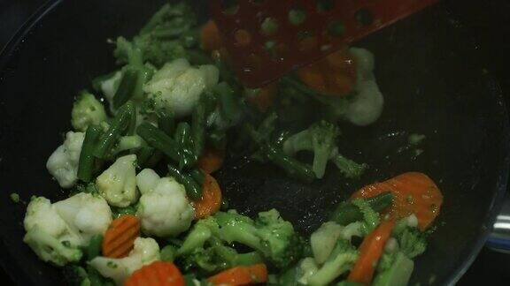 烹饪一个新鲜切好的蔬菜在煎锅上煎胡萝卜花椰菜花椰菜扁豆打开一个煎锅盖