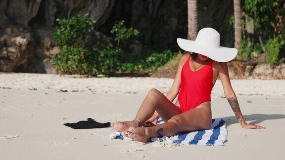 一名女子坐在沙滩上用智能手机自拍