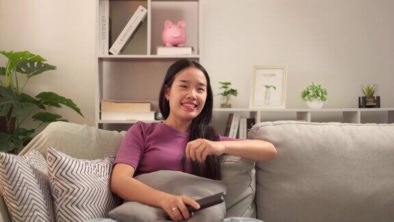 一个单身亚洲女性的生活方式在家里的客厅里愉快地放松和看电视