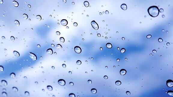 4k:在蓝天和云的背景下雨滴落在窗户上