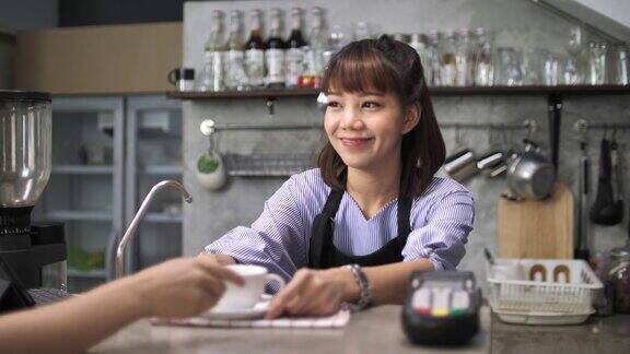 肖像微笑的咖啡师在咖啡店柜台上服务浓咖啡