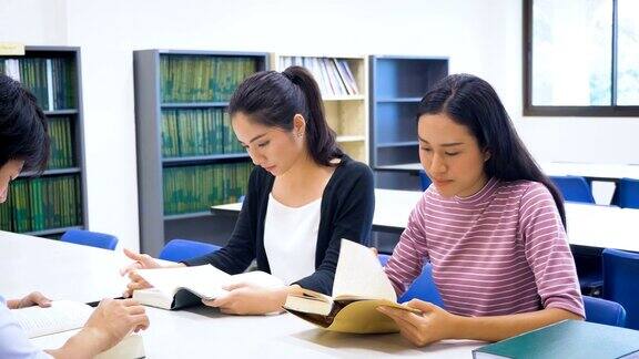 一群年轻的亚洲学生带着书在大学图书馆做研究学习教育和学校理念