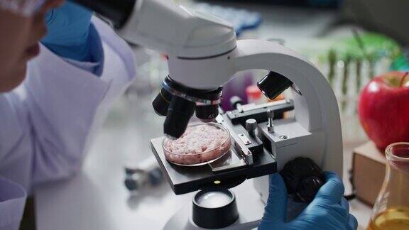 科学家正在实验室用显微镜对人工培养的肉样品进行检测和分析