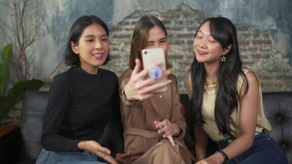 一群亚洲女性朋友聚在咖啡厅用智能手机自拍