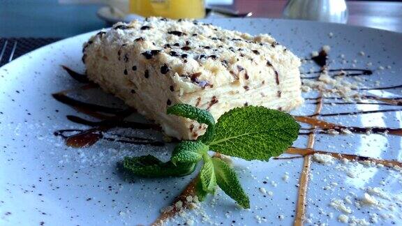 在一家餐馆或咖啡馆的桌子上一个盘子里放着一片由酥皮做成的拿破仑奶油蛋糕