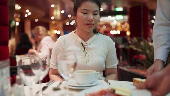 年轻迷人的亚洲旅游女子使用叉子和勺子感到饥饿快乐准备吃健康的食物看着豪华餐厅的食物