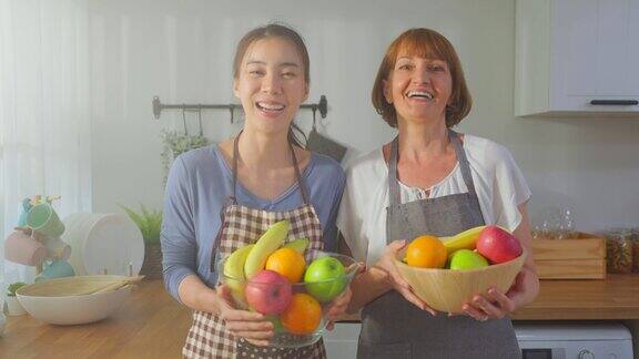 年轻女子和年长的祖母拿着一碗水果的肖像迷人美丽的女孩和年长成熟的母亲喜欢在家里吃干净的蔬菜来保持健康饮食与健康食品概念