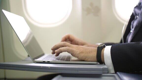 在上面工作商人在海外旅行时在飞机上使用笔记本电脑