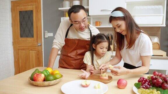 亚洲家庭帮忙做饭和妈妈一起在厨房剥苹果家庭关系概念