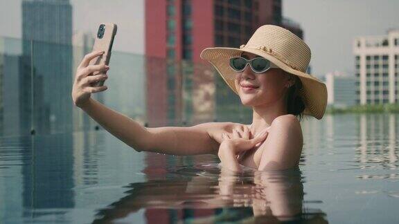 一名女子在泳池里用智能手机自拍