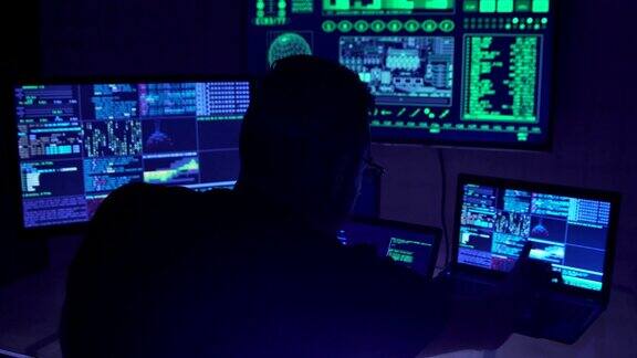 一名男性黑客在黑暗的办公室里摆弄电脑