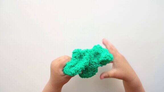 手玩带有气泡的有纹理的黏液拉伸粘稠物质女孩子手里捧着绿色发亮的黏液使劲捏着它可爱的宝宝把黏糊糊的玩具拉伸到两侧液体的玩具