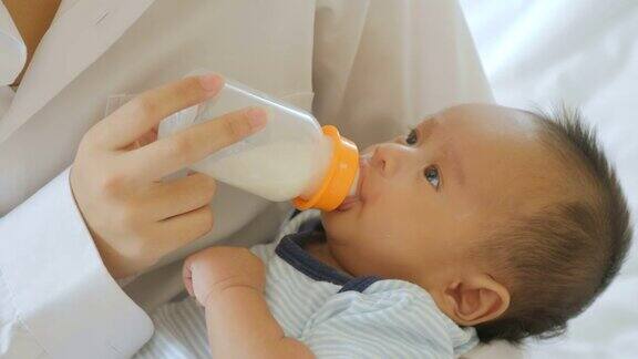 年轻的亚洲母亲在家用奶瓶喂男婴