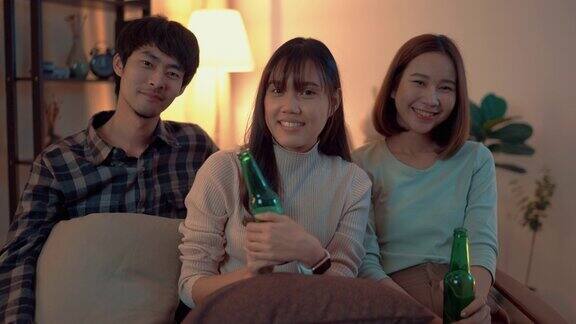 一群亚洲朋友喝啤酒和一起在周五晚上在公寓玩的肖像