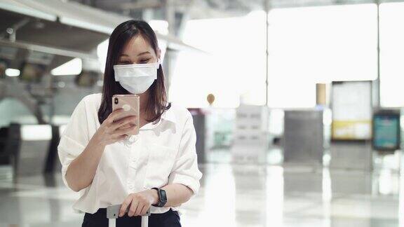 亚洲女性在机场使用智能手机时戴上防护口罩
