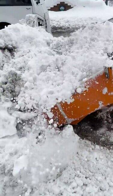 挖掘机一辆汽车在清理城市街道上的积雪